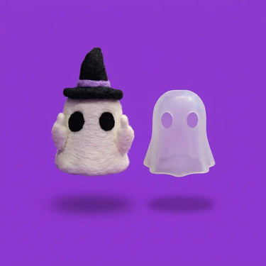 Needle felted Peeka ghost in a witch hat next to its frosted ghost-shaped Core
